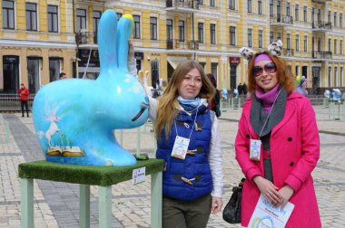 Gülümseyen kızlar, sokakta boyanmış Paskalya yumurtası gibi tavşanlara bakarlar. Halk sanatı festivali. 18 Nisan 2018. Kyiv, Ukrayna