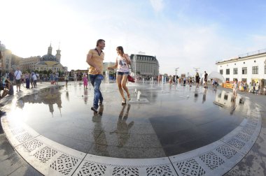 Şehirde güçlü bir sıcaklık var: insanlar meydanda çeşme suyu püskürterek oynuyorlar. 5 Haziran 2018. Kyiv, Ukrayna