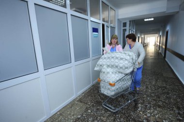 Laboratuvar önlüklü hemşireler, hastanenin cerrahi bölümünün lobisinde çarşaflı bir arabayı çekiyorlar. 12 Ocak 2019. Kiev Bölge Kliniği 1. Kiev, Ukrayna