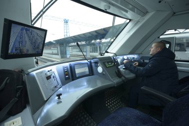 Yolcu treninin kabininde. Tren sürücüsü ön panelin önünde oturuyor ve elini başlama koluna koyuyor. 22 Aralık 2019. Kiev, Ukrayna