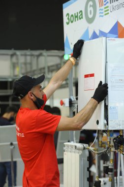 İnsan tesisatçısı modern gaz kazanını monte ediyor. Sergi Şenliği Ukrayna 'yı kurun. 1 Haziran 2021. Kyiv Ukrayna