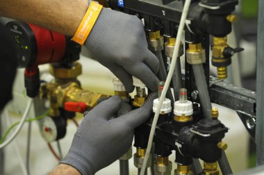 Tesisatçı eller ısıtma sisteminin ısıtma manifoldunu birleştiriyor, tiraj pompası Grundfos. Sergi Şenliği Ukrayna 'yı kurun. 1 Haziran 2021. Kyiv Ukrayna