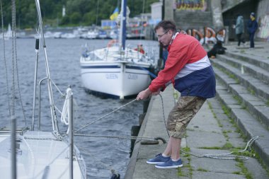 Yelkenli yat tayfası halat kullanarak bir rıhtıma demirlemiş. Şehir gününe adanmış amatör yelkenli yarışı. 30 Mayıs 2021. Kyiv, Ukrayna