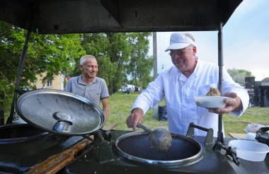 Seyyar mutfağın önünde durup bedava yemek hazırlayan insanlar için. Köyün günü. 12 Haziran 2021. Borysivka, Ukrayna