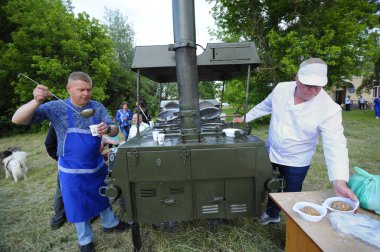 Seyyar mutfağın önünde durup bedava yemek hazırlayan insanlar için. Köyün günü. 12 Haziran 2021. Borysivka, Ukrayna