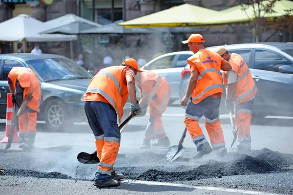 İşçiler şehrin caddesindeki yolu onarmayı durduruyorlar. 7 Ağustos 2021. Kyiv, Ukrayna