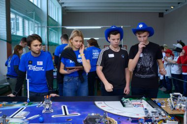 Young people students adjusting robot before launching it. School tournament among pupils. January 9, 2019. Kiev, Ukraine clipart