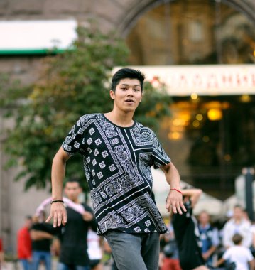 Young Asian boy street dancer performing on a street, crowd of people on a background. July 3, 2019. Kyiv, Ukraine clipart