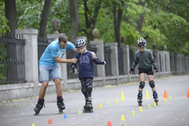 Paten kaymak. Çocuk hareketlerini düzelten antrenör sanatsal slalom öğretiyor. 25 Haziran 2019. Kyiv, Ukrayna