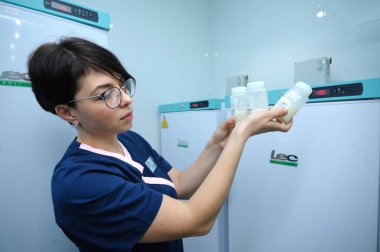 Laboratuvar asistanı içinde insan sütü olan anne sütü saklama kabı tutuyor. Arka planda da dondurucu var. 12 Nisan 2019. Kiev, Ukrayna