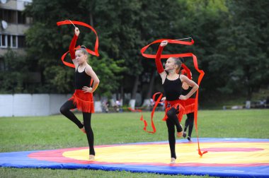 Bir grup küçük artistik jimnastik kızı stadyumda kurdelelerle gösteri yapıyor. 20 Haziran 2019. Kyiv, Ukrayna