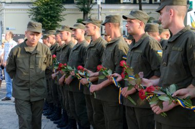 Askeri üniformalı Ukraynalı askerler Ukrayna Düşmüşleri Anma Duvarı 'na koymak için ellerinde kırmızı çiçek buketleri tutuyorlar. 28 Ağustos 2018. Kyiv, Ukrayna