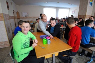 Engelli çocuklar için yatılı okulun kantininde. Down sendromlu çocuklar akşam yemeğinden önce masada otururlar. 12 Şubat 2019. Kiev, Ukrayna
