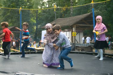 Müslüman Kırım Tatarı çocuklar küçük erkek çocuklar tesettürlü kızlar oyun parkında oynuyorlar. Hidirellez 'in kutlaması. 19 Mayıs 2018. Kiev, Ukrayna