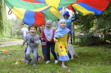 Müslüman Kırım Tatarı çocuklar küçük erkek çocuklar tesettürlü kızlar oyun parkında oynuyorlar. Hidirellez 'in kutlaması. 19 Mayıs 2018. Kiev, Ukrayna