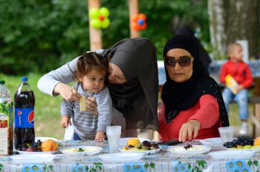 Yemek masasında oturan tesettürlü Müslüman kadınlar. Hidirellez 'in kutlaması. 19 Mayıs 2018. Kiev, Ukrayna