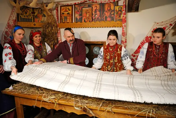 Ukrayna ulusal kostümlü insanlar Noel arifesi için masayı hazırlıyorlar. Eski kır evi, halk geleneklerinin yeniden inşası. 4 Ocak 2018. Kyiv, Ukrayna