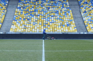Çim biçme makinesiyle futbol sahasında çim biçen bir işçi. 16 Mart 2018. Kyiv, Ukrayna