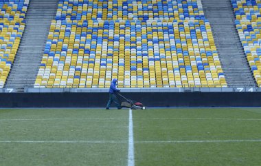 Çim biçme makinesiyle futbol sahasında çim biçen bir işçi. 16 Mart 2018. Kyiv, Ukrayna