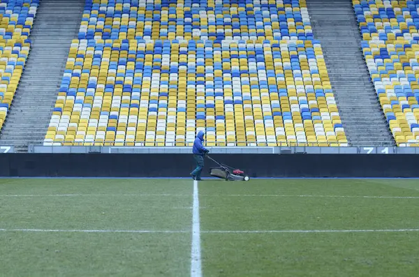 Çim biçme makinesiyle futbol sahasında çim biçen bir işçi. 16 Mart 2018. Kyiv, Ukrayna