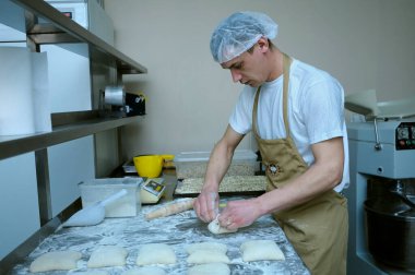 Fırında: fırıncı çalışma masasında duruyor ve ekmek pişirmek için hamur kalıbı çıkarıyor. 21 Mart 2018. Brovary, Ukrayna