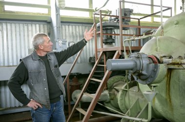 Pompa istasyonunun elektrik pompasına dokunarak etrafta aylaklık eden bir işçi. 5 Mayıs 2018. Oseschina, Ukrayna