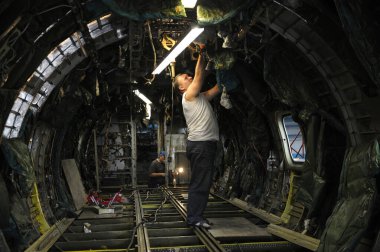 İşçi bir uçağın içine yeni elektrik kabloları yerleştiriyor. Eyalet Uçak Tamir Tesisi 410. 8 Haziran 2018. Kiev, Ukrayna