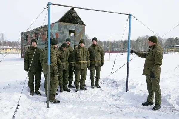 Stock image Team-building exercise: soldiers holding their fellow on hands pushing him through net. February 1, 2018. Military range, Novo-Petrivtsi, Ukraine