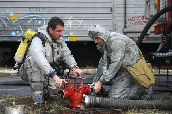 stock image Rescue team training of chemical decontamination: rescuer in a protective ensemble turning a valve of a fire hydrant to water plant territory. February 21, 2019. Kiev, Ukraine