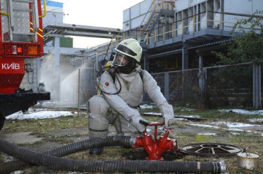 İtfaiyeciler itfaiye ekipmanlarını yerleştiriyor, itfaiye kamyonu fabrika bölgesini sulamaya hazır, eğitim görüyor. 21 Şubat 2019. Kyiv, Ukrayna