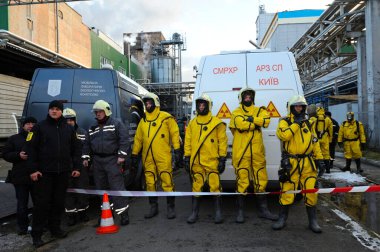 Kurtarma ekibi eğitimden sonra koruyucu kostümlerle ayakta duruyor. Arka planda mobil kimya laboratuvarı var. 21 Şubat 2019. Kyiv, Ukrayna