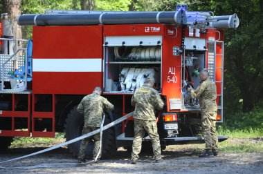 İtfaiye aracı park etmiş, itfaiyeciler yangın söndürme ekipmanlarını kullanıma hazırlıyor. 5 Haziran 2019. 2019. Kievskaya oblast, Ukrayna