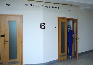 Yüz maskeli hemşire ve laboratuvar önlüğü bir hastanenin kapısını açıyor. 2 Şubat 2020. Kiev, Ukrayna