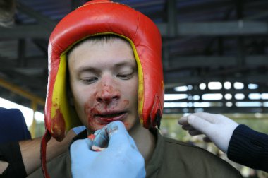 Cutman doktoru dövüşçü burnunun kanamasını durdurdu. Asker kavgası, erkekler, subay eğitmenleri ve acemi askerler arasındaki gösteri kavgası, amatörler. 18 Ekim 2018. Novo-Petrivtsi askeri üssü, Ukrayna