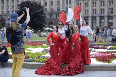 Parlak kırmızı çingene kostümlü bir grup kadın fotoğrafçının önünde poz veriyor. 5 Haziran 2021. Kiev, Ukrayna