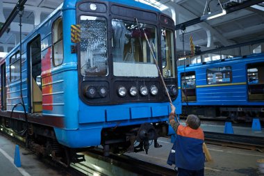 Bakım salonu: Çukurda park etmiş bir metro treninin camlarını yıkayan kadın işçi. Metro vagonu Obolon, Kiev, Ukrayna 'da. 22 Kasım 2018