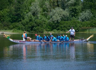Kürekçiler nehirde ejderha teknesiyle kürek çekiyor. Amatörler arasında Kiev Oblast şampiyonası. 25 Mayıs 2020. Kiev, Ukrayna