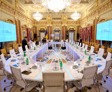 Assistants preparing the main meeting hall of Mariyinsky Palace for event. Oval table, monitor, microphones, flags. May 25, 2018. Kyiv, Ukraine clipart