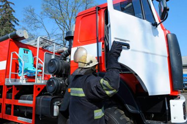Koruyucu kostümlü itfaiyeci bir itfaiye aracının kabinine girdi. Kurtarma ekibi itfaiyecilik eğitimi alıyor..