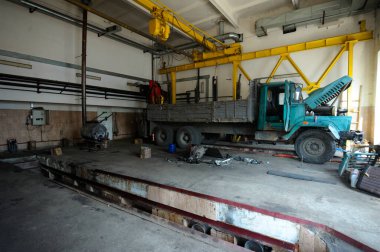 Araba tamircisi atölyesi. Çok eski bir kamyon tamir ediliyor. Araç kontrol çukuru, kaldırma ve motor söküldü..