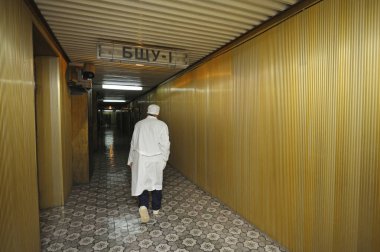 Worker in protective cloth going down the passageway of the Chernobyl Nuclear Power Plant. Chernobyl, Ukraine clipart