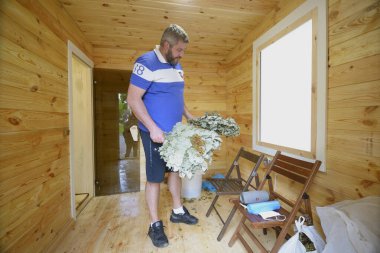 Buhar banyosuna hazırlanıyorum. Hamamın ahşap soyunma odasında elinde banyo masajı süpürgesiyle duran bir adam. 15 Mayıs 2021. Kyiv, Ukrayna