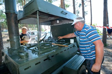 Seyyar tarla mutfağının önünde durup kampta turistlere yemek pişirmek. 20 Temmuz 2021. Pereyaslav-Khmelnytsky, Ukrayna