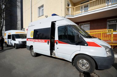 Arka planda Aleksandrovskaya Hastanesi 'nin enfeksiyon hastalıkları bölümü binası olan iki ambulans aracı park etmiş. 26 Şubat 2020. Kiev, Ukrayna