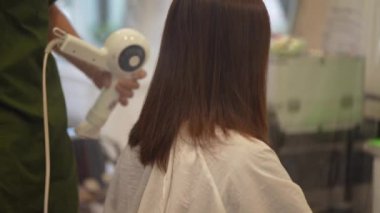 Male hairdresser drying woman's hair with hairdryer