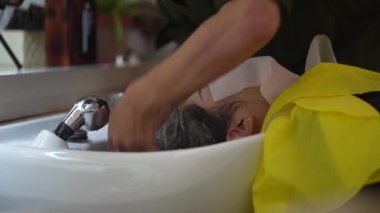 Erkek kuaför kadının saçını yıkıyor.