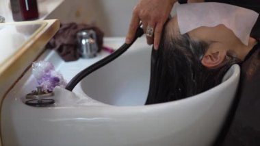 Erkek kuaför kadının saçını yıkıyor.
