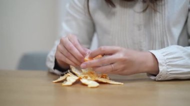 A woman who peels and eats a mandarin orange