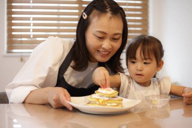 Parents and children putting toppings on hot cakes