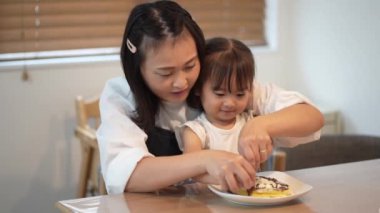 Parents and children putting toppings on hot cakes